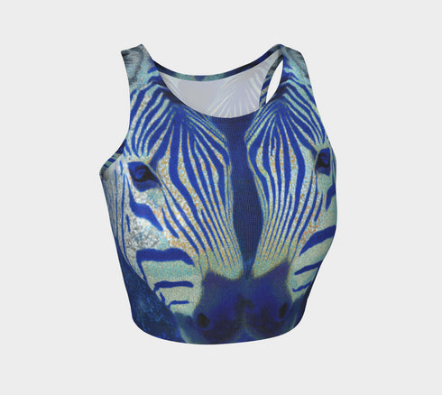 A women's sleeveless, high-neck crop top made from a performance spandex knit fabric. The top is designed with a body-hugging fit and features a striking, symmetrical digital graphic of a zebra's face. The intricate print uses shades of electric blue, cobalt, and navy, contrasted with a shimmering silver glitter effect that outlines the zebra's stripes and features. The psychedelic, futuristic design covers the entire front of the shirt.